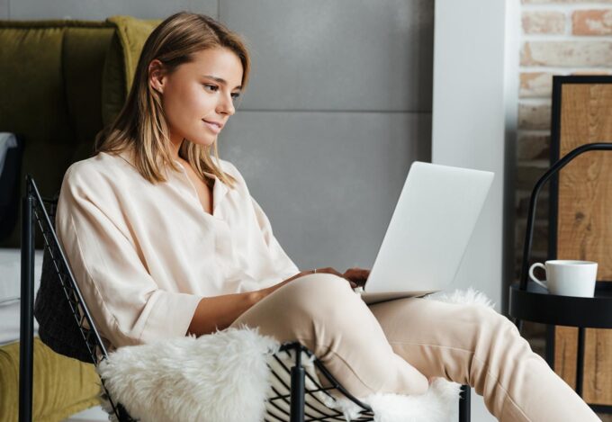 Woman sitting in chair at laptop researches assumable mortgage loans.