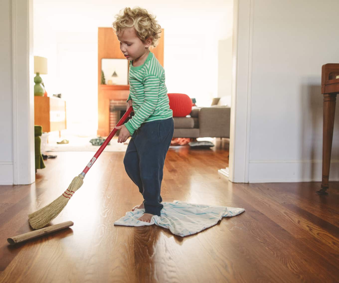 Child playing with broom in family home
