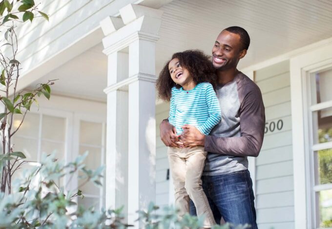 Father and daughter stand outside of their new home.