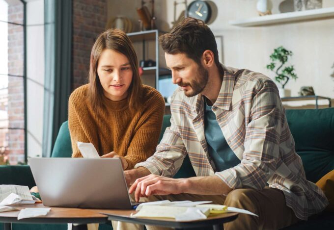 Couple sitting together on couch calculates what percent of their income should go to their mortgage.