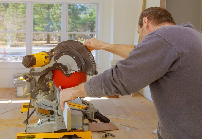 Image of a man using a saw while doing a home improvement project.